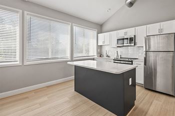 A kitchen with a large island and a stainless steel refrigerator