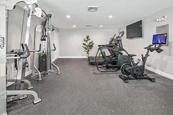 A gym with exercise equipment and a tv on the wall