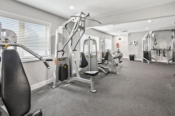 A gym with cardio machines and weights in a room with a window