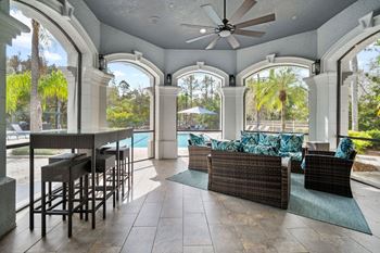 A patio with a table and chairs overlooking a pool.