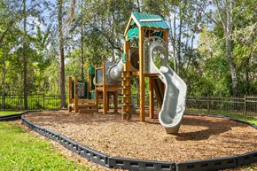 Tampa apartment for rent - A playground with a green roofed structure and a grey slide at The Grand Reserve at Tampa Palms Apartments, Tampa, Florida