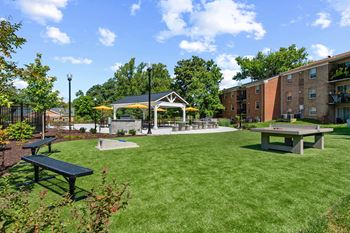 A park with picnic tables and a gazebo in front of a building