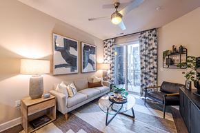Raleigh townhouse for rent - A living room with a couch, a coffee table, and a ceiling fan at The Edison Lofts Apartments, Raleigh