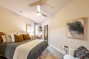 Raleigh townhouse for rent - A bedroom with a large bed and a ceiling fan at The Edison Lofts Apartments, Raleigh, 27601
