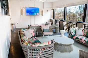 A rooftop lounge with wicker furniture and a television