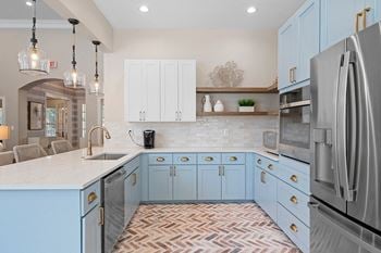A kitchen with blue cabinets and a sink and a refrigerator