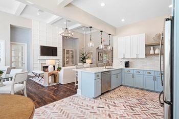 A kitchen with blue cabinets and a living room with a table and chairs
