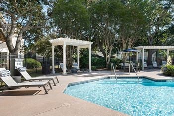 A swimming pool with chairs and umbrellas next to a resort style pool