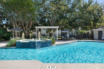 A large swimming pool with a jacuzzi and some trees