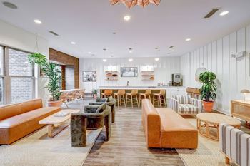 A modern resident clubroom with a variety of seating options and a long wooden table.