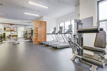A gym with a variety of equipment including treadmills and weights.