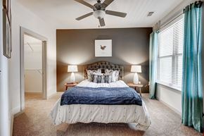 Davidson apartment for rent - A bedroom with a bed, two lamps, and a ceiling fan at The Linden Apartments, Davidson, NC, 28036