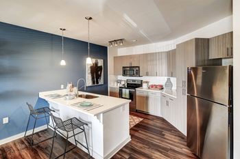 A kitchen with a white island and a stainless steel refrigerator.