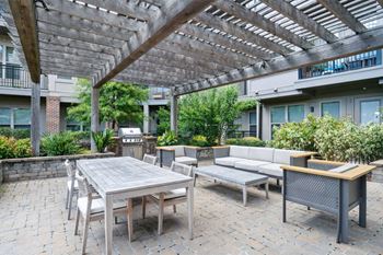 A patio with a table and chairs under a wooden pergola.