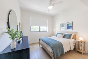 Miami Lakes apartment for rent - A bedroom with a bed, a dresser, a mirror, and a plant.