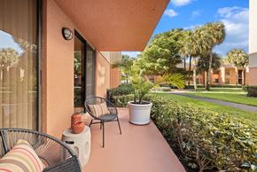 Miami Lakes apartment for rent - a balcony with two chairs and a table and a yard with palm trees