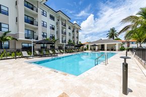 Miami Lakes apartment for rent - A large swimming pool in front of a building with a black umbrella.