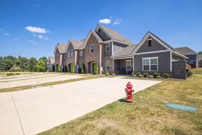 Opelika townhouse for rent - A red fire hydrant sits on a green patch of grass in front of a grey house.