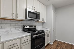 Auburn apartment for rent - A kitchen with white cabinets and a black stove top oven.