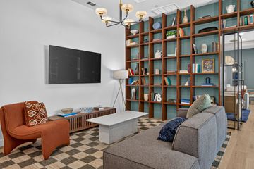 San Antonio apartment for rent - A living room with a grey couch, a brown chair, and a television on the wall.