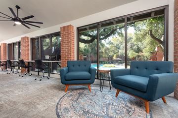 Austin apartment for rent - a living room with blue chairs and a rug and a large window