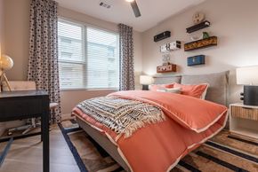 Lakewood apartment for rent - A bedroom with a bed covered in an orange blanket.