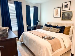 Spring Hill apartment for rent - A bedroom with a large bed and a window with blue curtains.