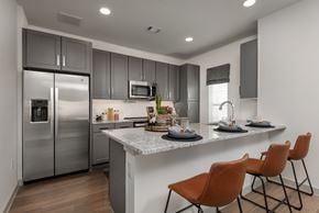 Fort Worth townhouse for rent - A modern kitchen with a refrigerator, microwave, and a counter with chairs.