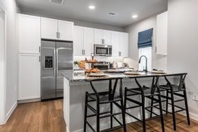 Schertz townhouse for rent - A kitchen with a refrigerator, microwave, and a table with chairs.