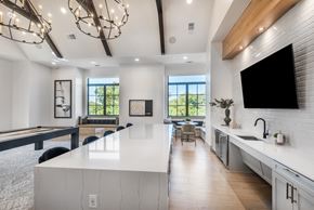 Boerne townhouse for rent - A modern kitchen with a pool table and a view of trees outside the window.