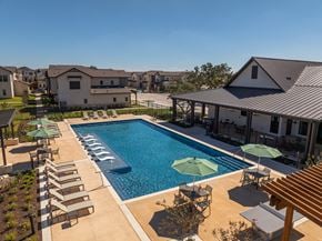 Boerne townhouse for rent - A large swimming pool surrounded by lounge chairs and umbrellas.