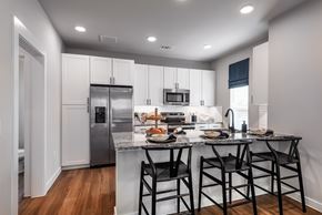 Fort Worth townhouse for rent - A kitchen with a refrigerator, microwave, and a counter with a table and chairs.