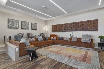 San Antonio apartment for rent - A modern living room with a large sectional sofa and a wooden wall panel.