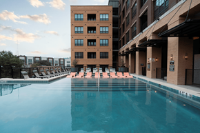 San Antonio apartment for rent - A large swimming pool in front of a building with lounge chairs around it.