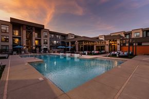 Goodyear apartment for rent - A swimming pool in front of a building with lights on.