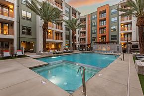 Phoenix apartment for rent - A swimming pool in front of apartment buildings with palm trees.