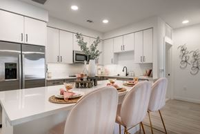 Denver apartment for rent - A modern kitchen with white cabinets and a dining table set for two.