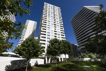 Toronto apartment for rent - A tall white building stands in front of two other buildings.