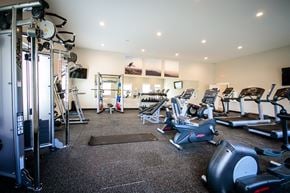 Uniontown apartment for rent - a gym with cardio equipment and weights on the floor