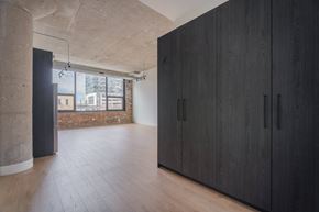 Chicago apartment for rent - A room with black cupboards and wooden floors.