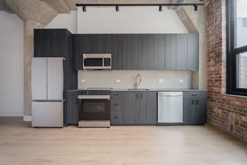 Chicago apartment for rent - A kitchen with a white fridge, black cabinets, a white oven, a white dishwasher, and a white microwave.
