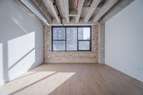 Chicago apartment for rent - A room with wooden floors and a window with a view of a building outside.