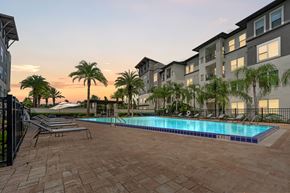 Orlando apartment for rent - A swimming pool surrounded by palm trees and apartment buildings.