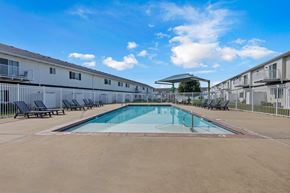 Sioux Falls townhouse for rent - A swimming pool in a sunny day surrounded by chairs and buildings.