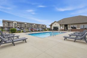 Sioux Falls townhouse for rent - A swimming pool surrounded by lounge chairs in front of apartment buildings.