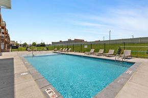 Rapid City apartment for rent - a swimming pool with lounge chairs and a building in the background