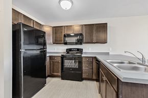Rapid City apartment for rent - a kitchen with black appliances and wooden cabinets