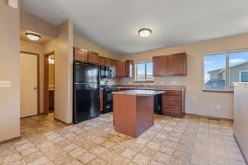 Sioux Falls townhouse for rent - A kitchen with a black refrigerator and wooden cabinets.