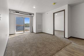 Sioux Falls apartment for rent - A spacious room with a carpeted floor and a sliding glass door leading to a balcony.