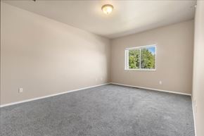 North Sioux City apartment for rent - A room with a grey carpet and a window showing trees outside.